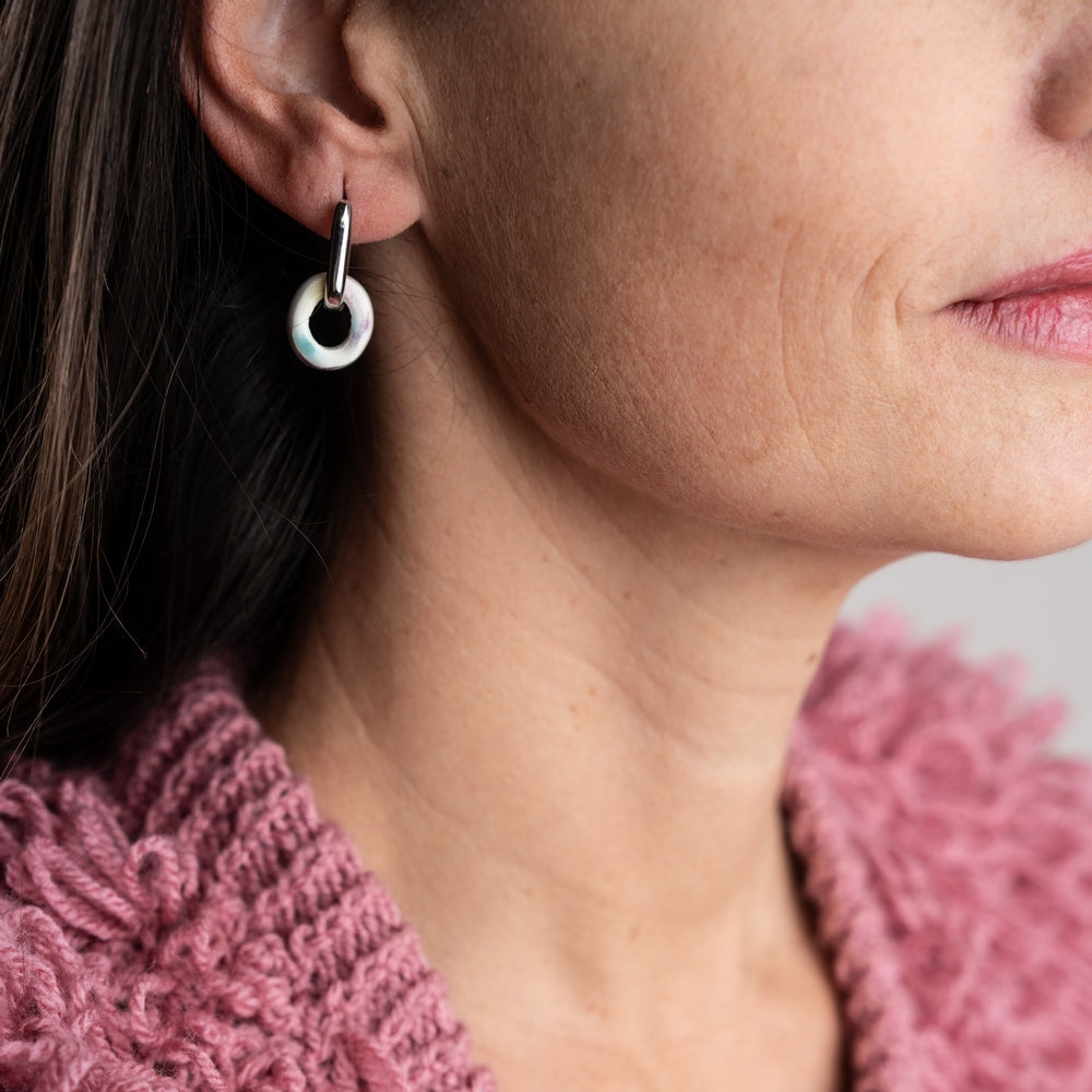 Close-up of a person wearing a pink knitted sweater and silver hoop earrings.