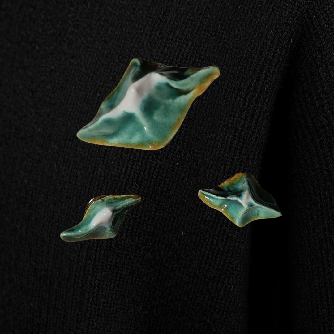 Three green ceramic pins on a black background