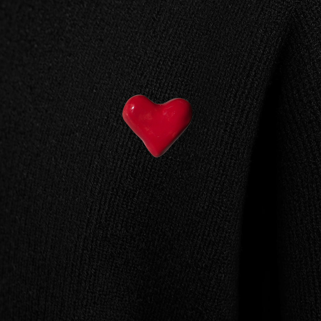 Red heart-shaped pin on a black background