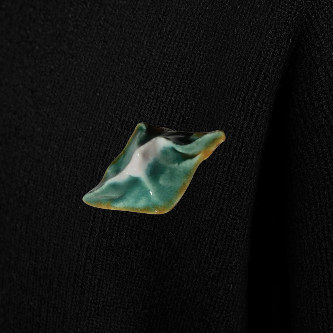 Green leaf-shaped brooch on a black sweater