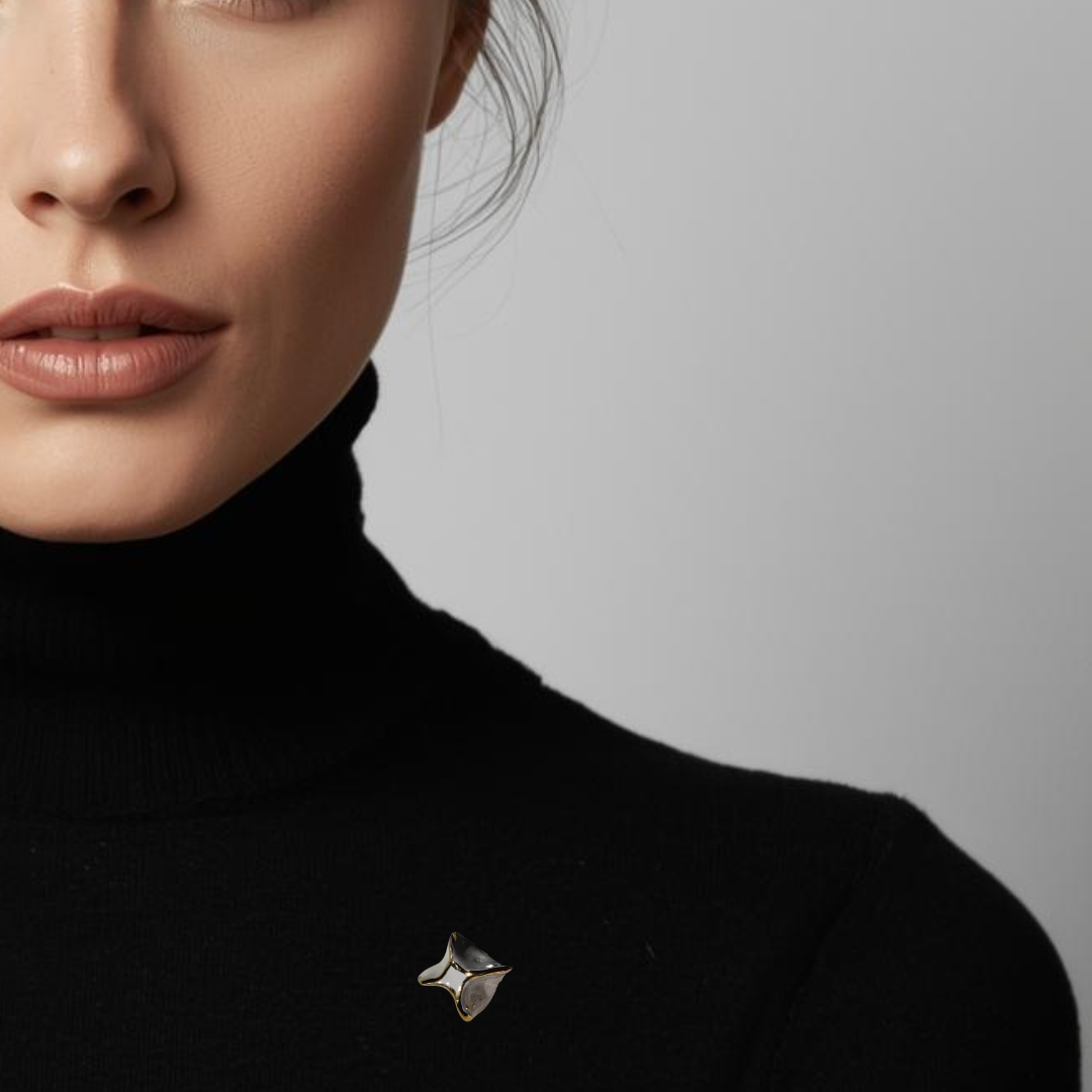 Close-up of a person wearing a black turtleneck with a star-shaped brooch on a neutral background