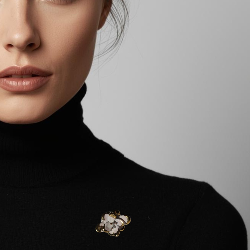 Close-up of a person wearing a black turtleneck with a decorative brooch on a neutral background