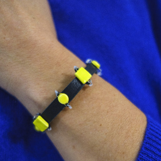 Bracelet with yellow accents on a wrist against a blue background