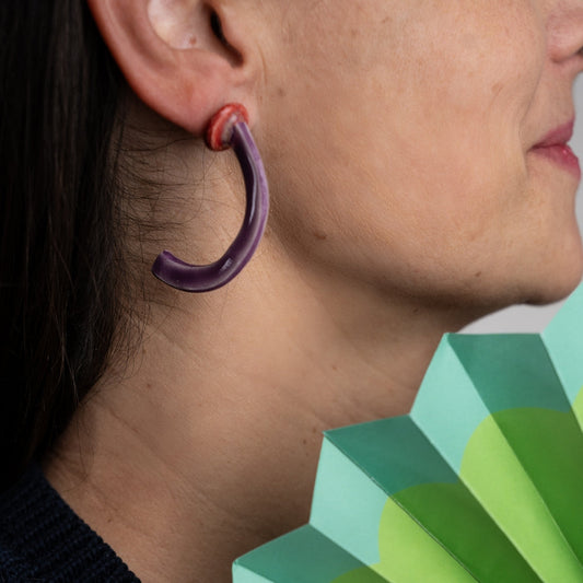 Close-up of a person wearing a purple hoop earring.