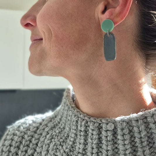 Woman wearing a gray knitted sweater with a close-up of her earrings.