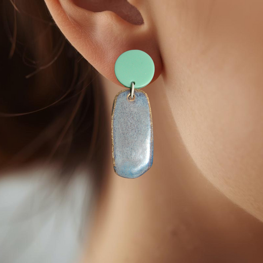 Close-up of an ear wearing a mint green and gray earring.