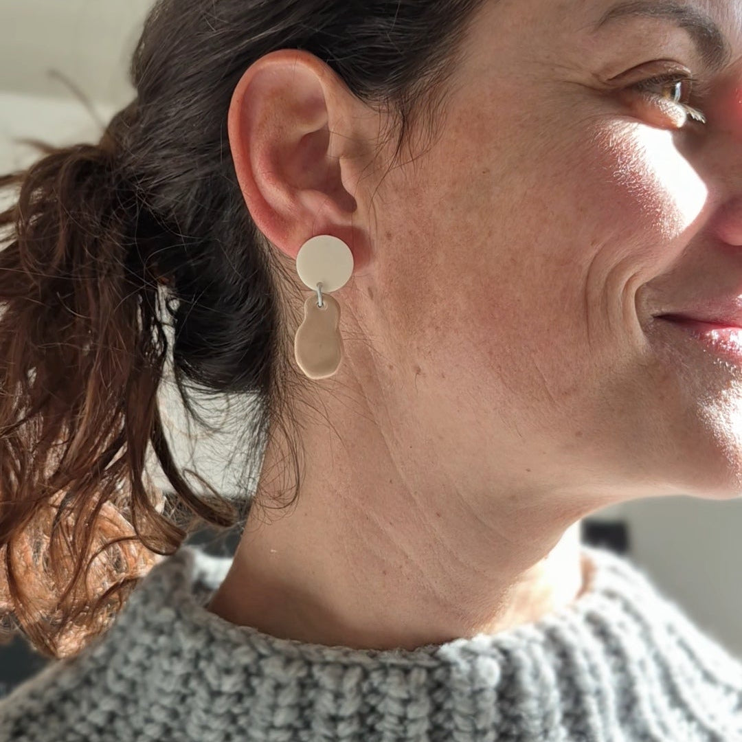 Close-up of a woman wearing gold hoop earrings with a neutral background