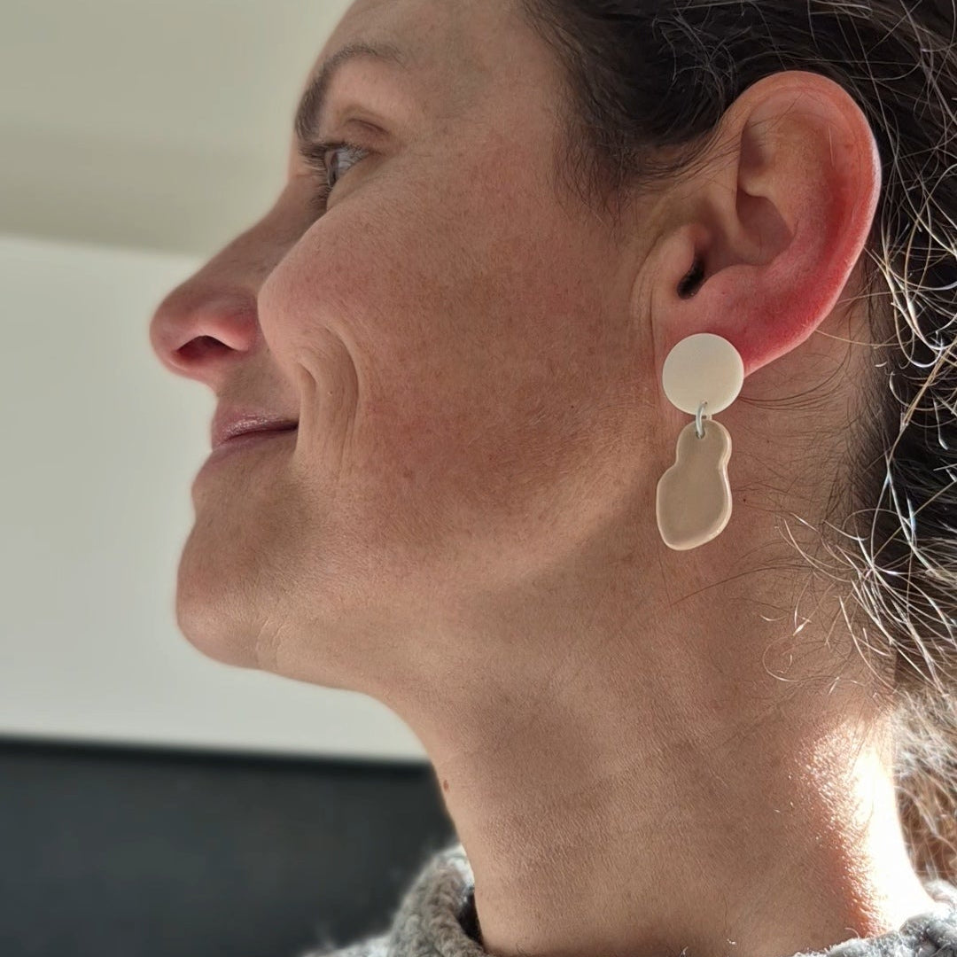 Close-up of a person wearing a silver earring, with a neutral background