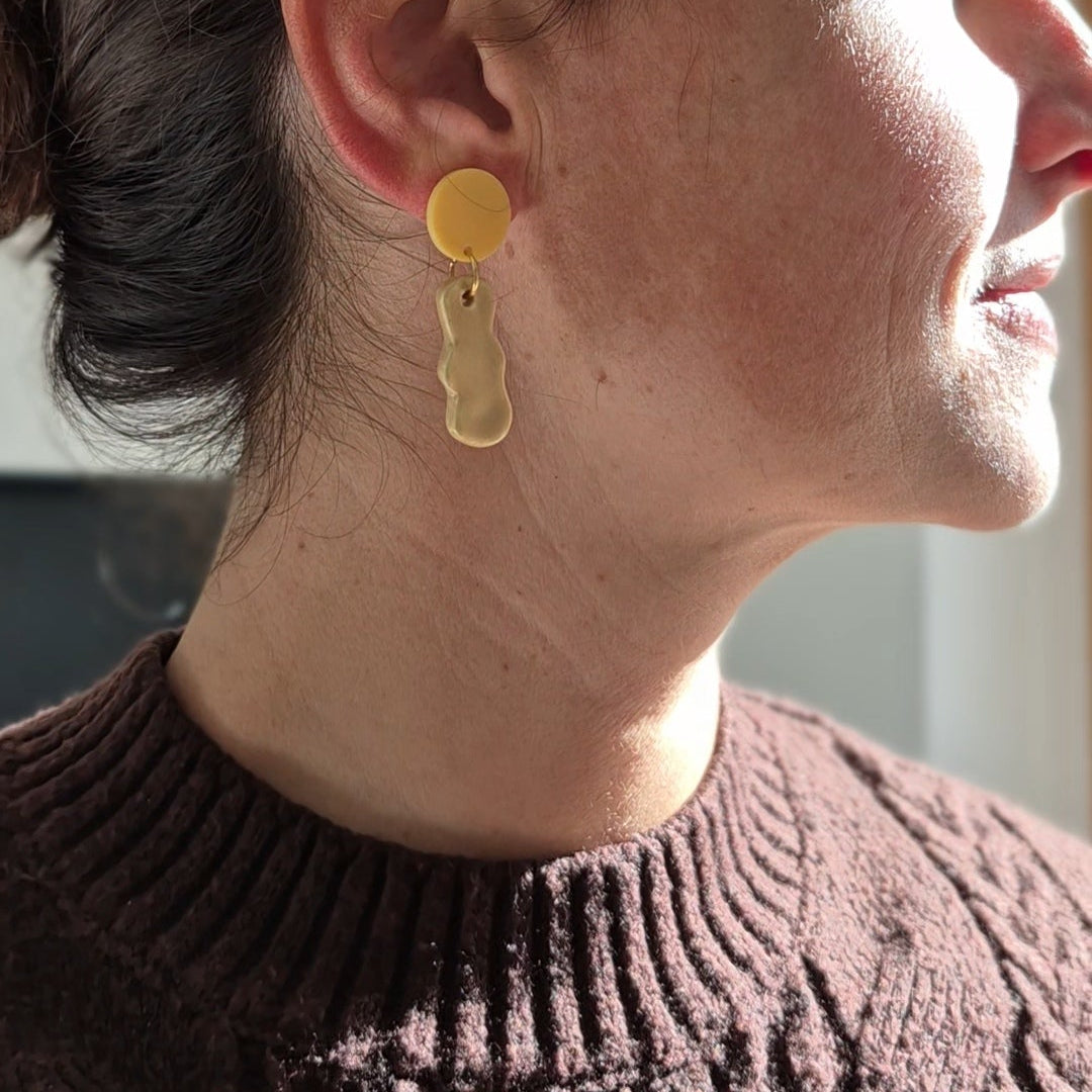 Close-up of a person wearing a gold -ceramic earring indoors