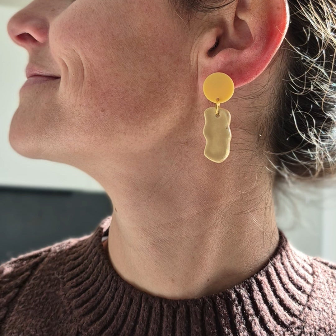 Woman wearing gold earrings with a blurred background