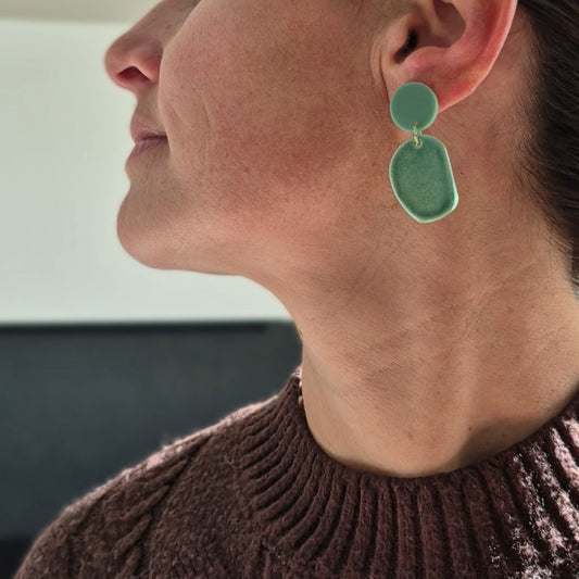 Woman wearing green earrings with a blurred background