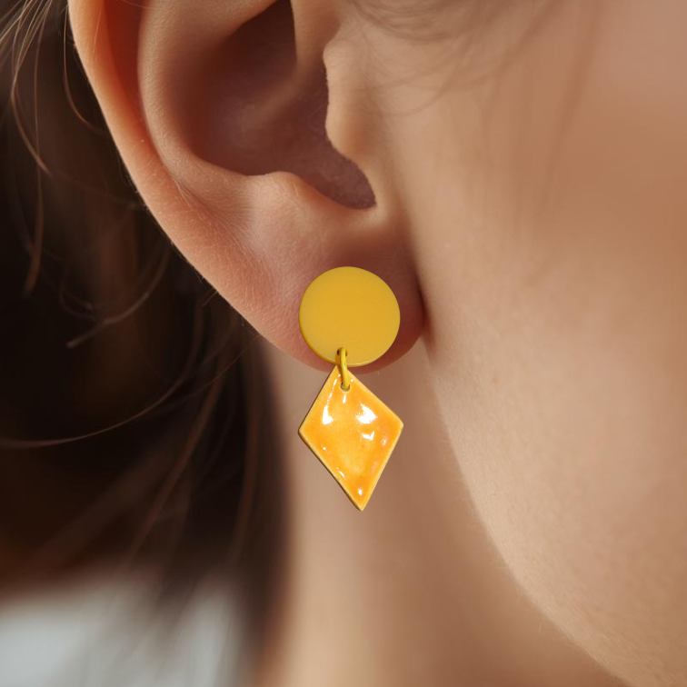Close-up of a person wearing yellow earrings with a blurred background