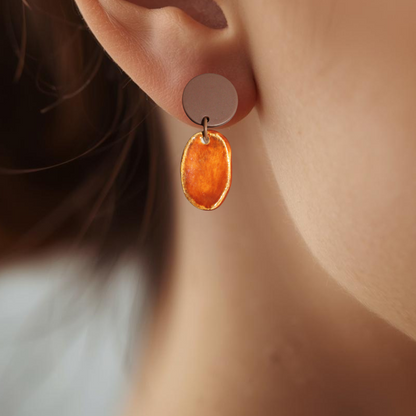 Close-up of an ear wearing a round brown earring with a blurred background