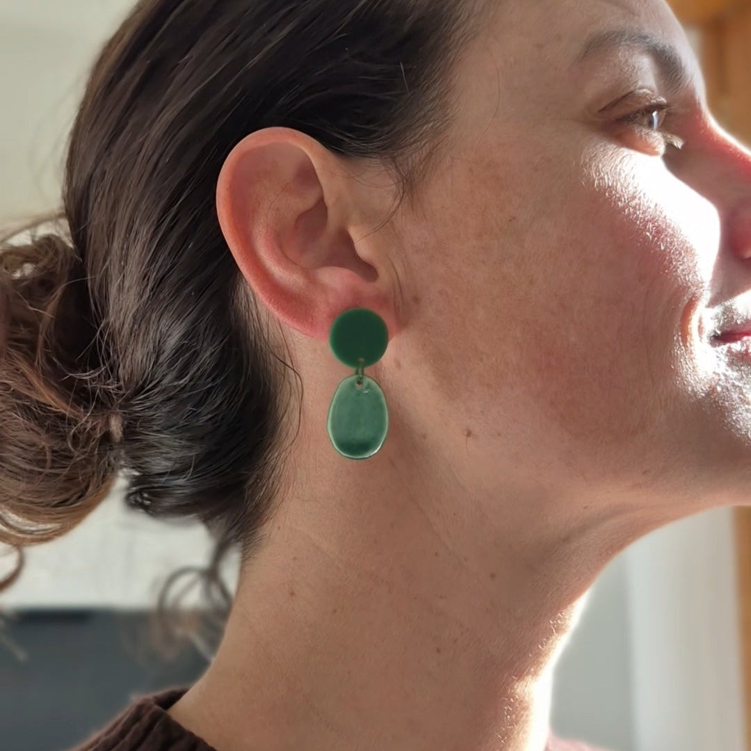 Close-up of a person wearing green earrings with a blurred background