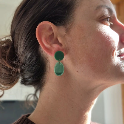 Close-up of a person wearing green earrings with a blurred background