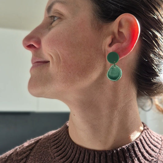 Woman wearing green earrings with a blurred background