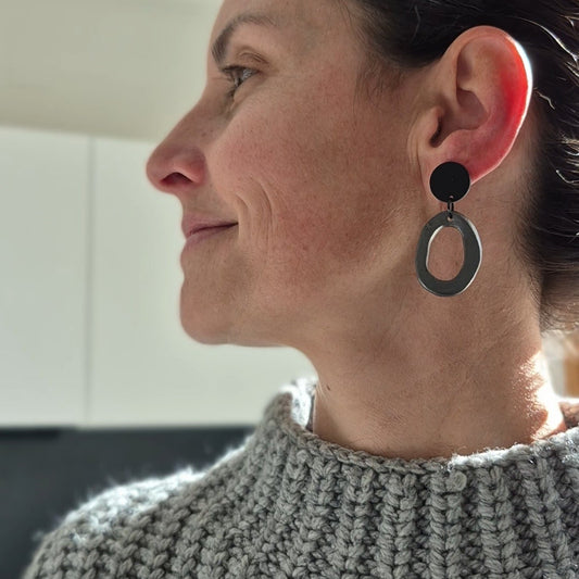 Woman wearing black hoop earrings in a neutral indoor setting