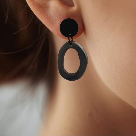 Close-up of an ear wearing a black hoop earring with a blurred background