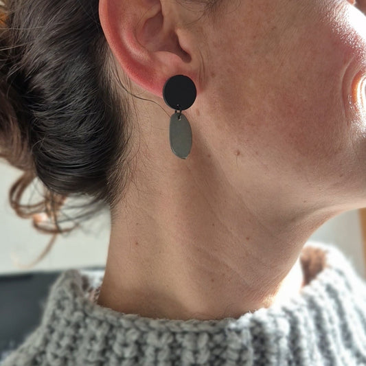 Close-up of a person wearing black and gray earrings.