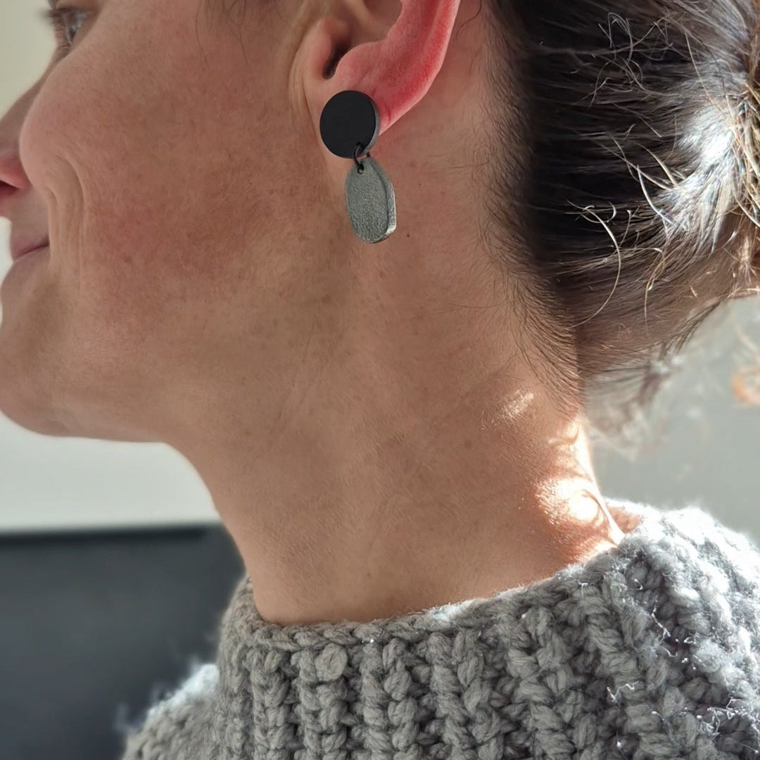 Woman wearing a gray knitted sweater with earrings.