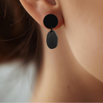 Close-up of an ear wearing black earrings with a blurred background