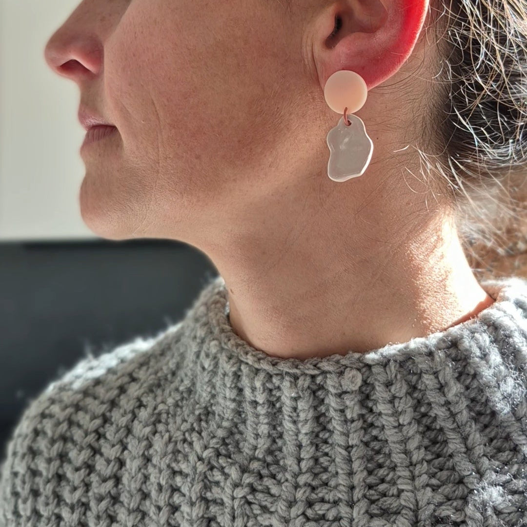 Close-up of a person wearing a unique earring with a textured surface.