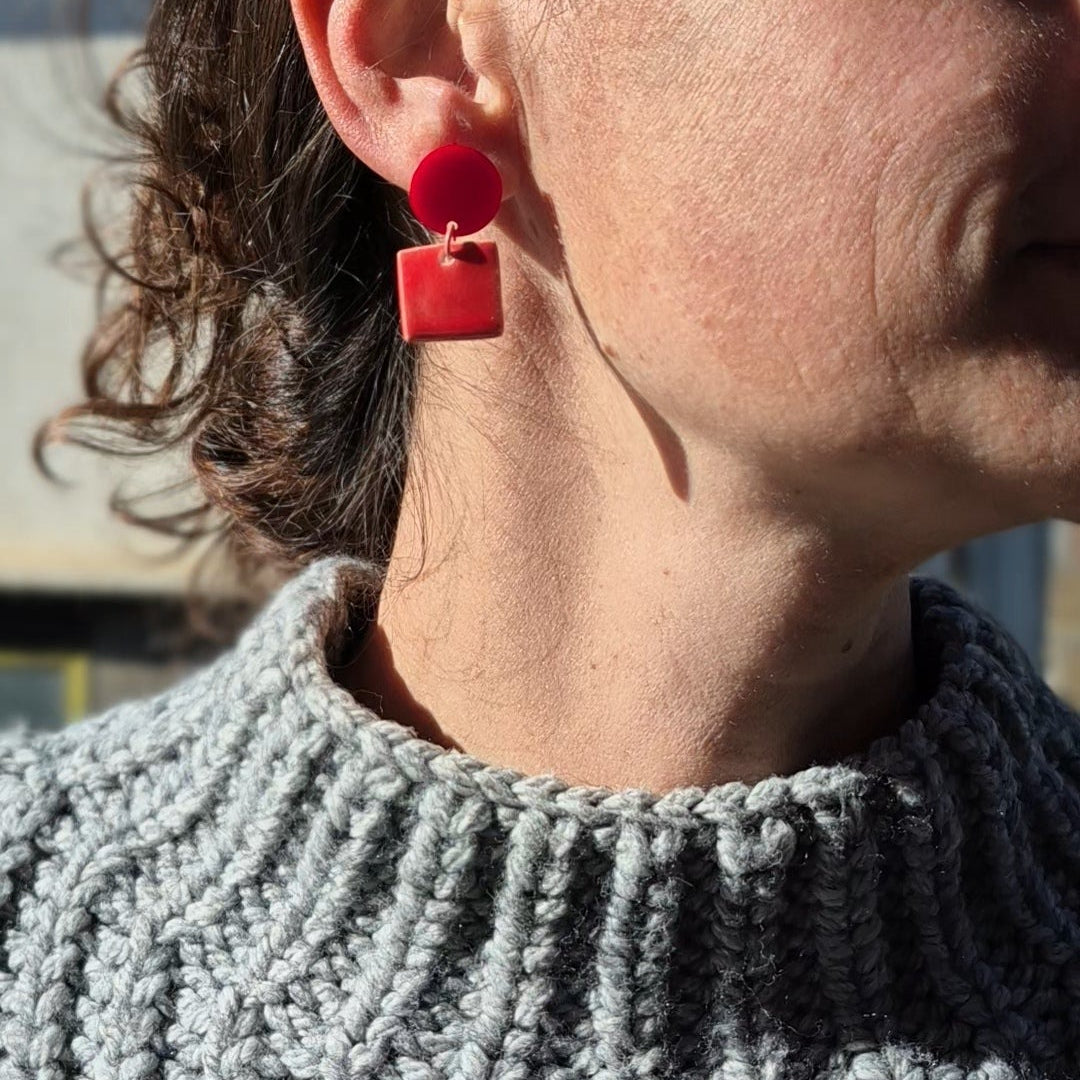 Close-up of a person wearing red earrings with a blurred background