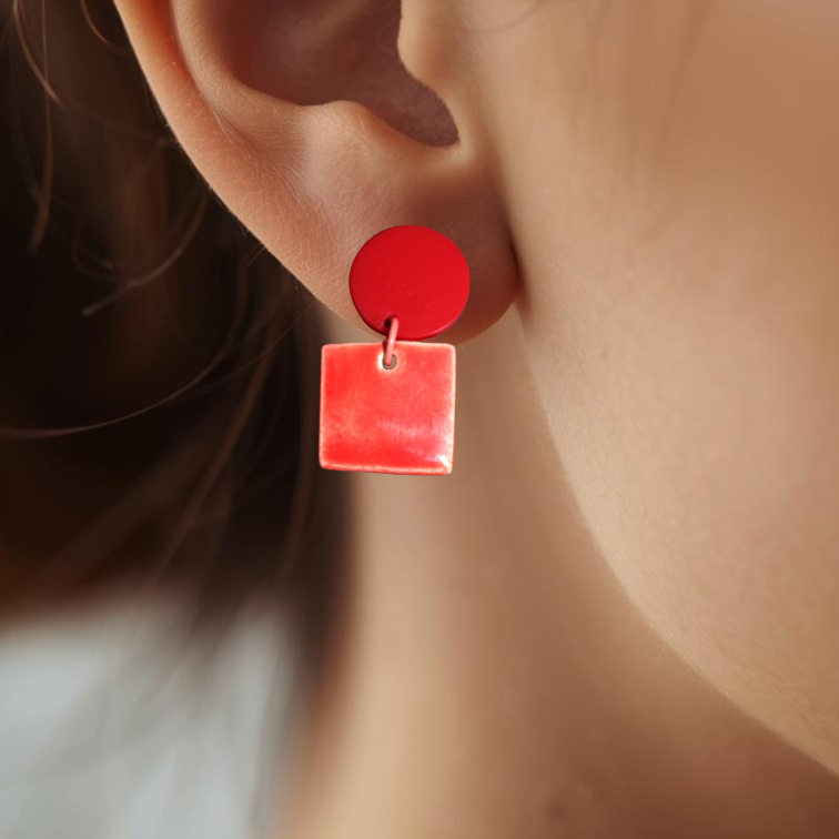 Close-up of a person wearing red square earrings.