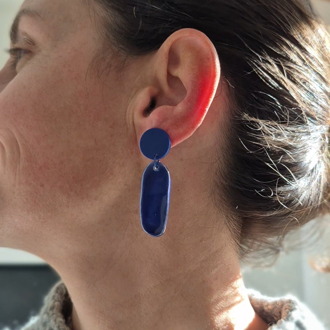 Person wearing a blue earring with a neutral background