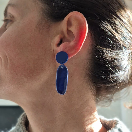 Person wearing a blue earring with a neutral background