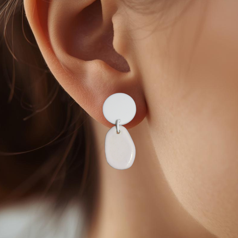 Close-up of an ear wearing a white earring with a blurred background