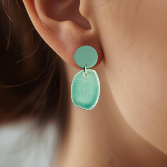 Close-up of an ear wearing a green earring with a blurred background