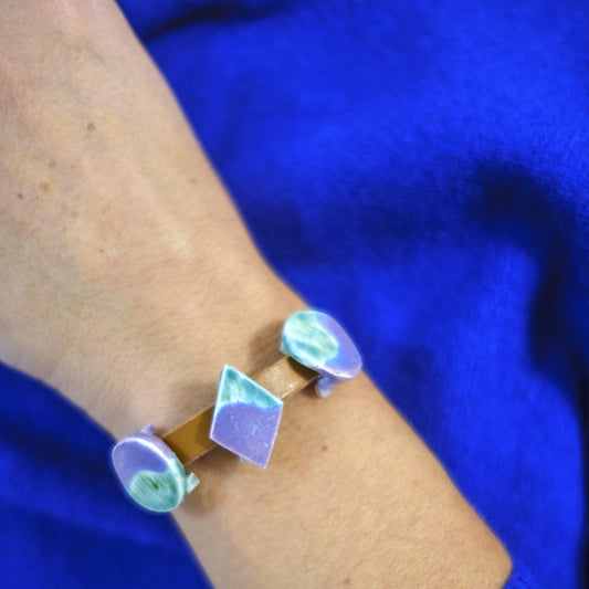 Bracelet with geometric design on a wrist against a blue background