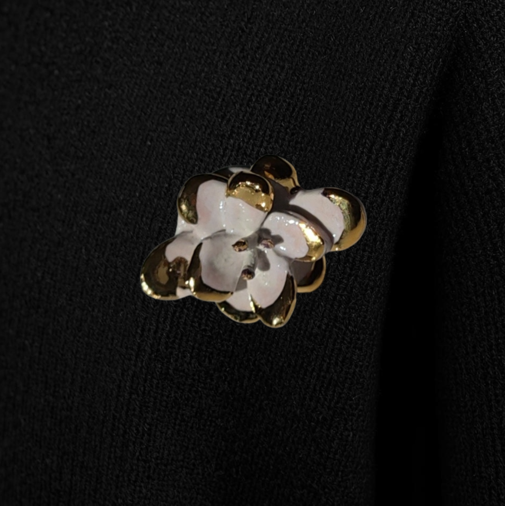 Floral brooch with gold and white details on a black background