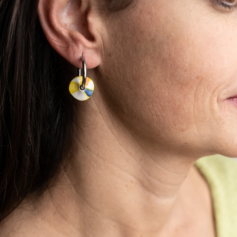Close-up of a woman wearing colorful hoop earrings with a blurred background
