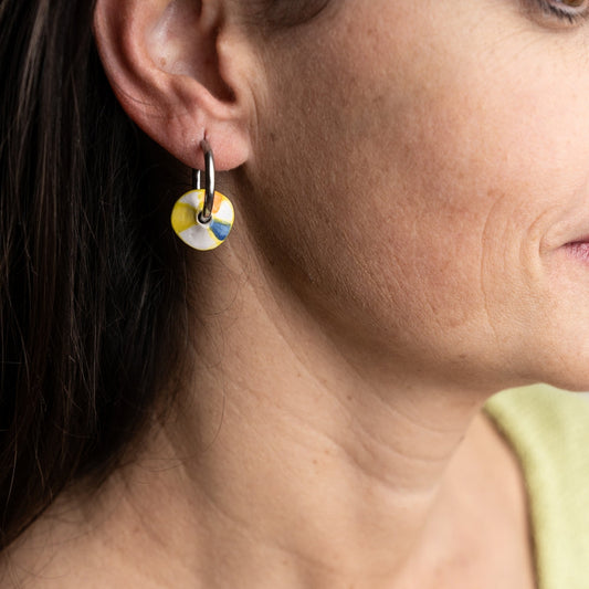 Close-up of a woman wearing colorful hoop earrings with a blurred background