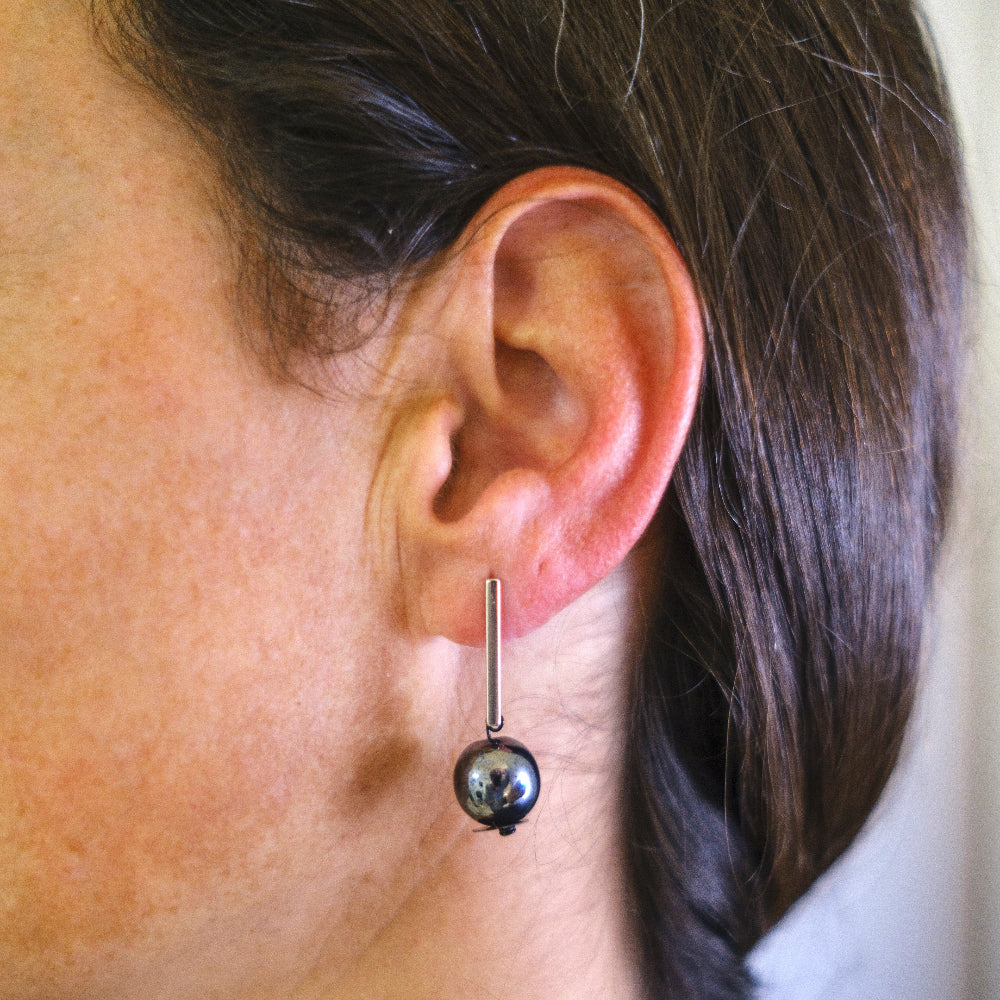 Close-up of an ear wearing a barbell earring with a spherical end.