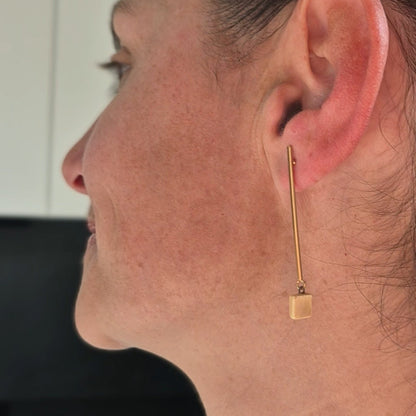 Close-up of a person wearing a gold earring indoors.
