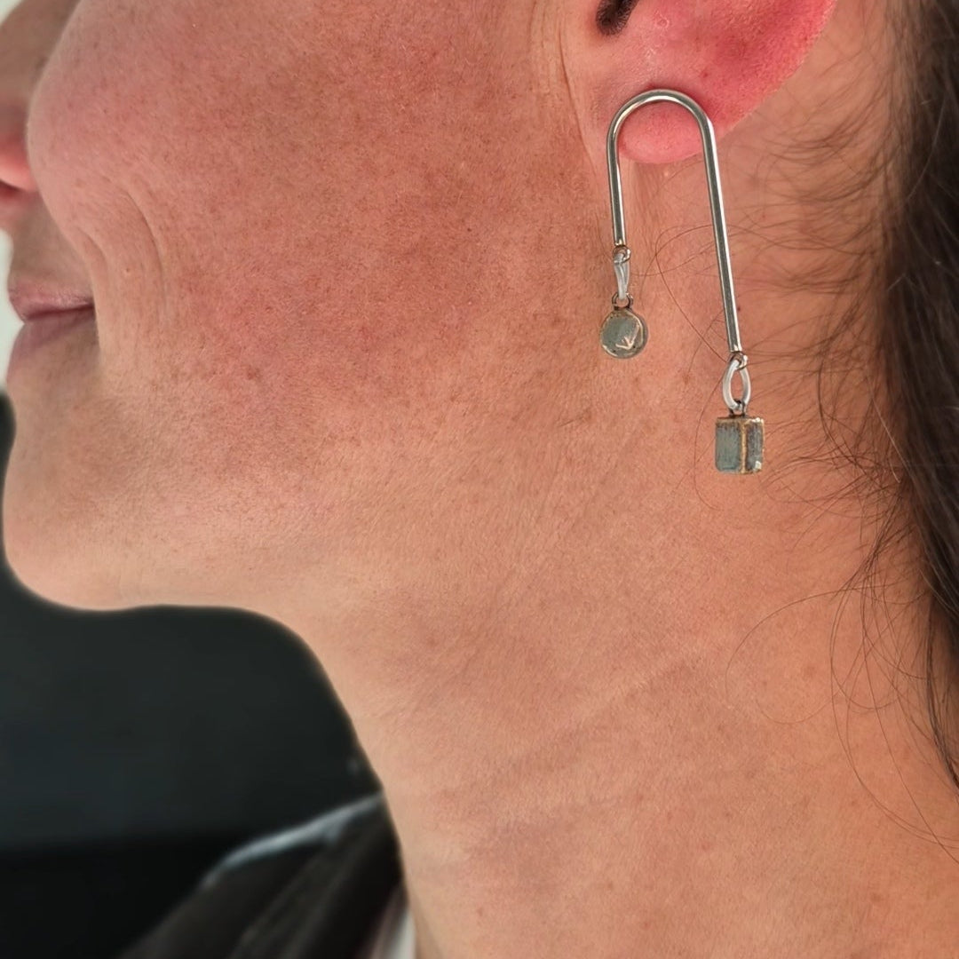 Close-up of a person wearing a unique earring with a U-shaped design.