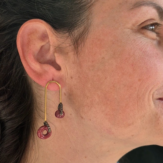 Close-up of a person wearing gold earrings with metalic beads.