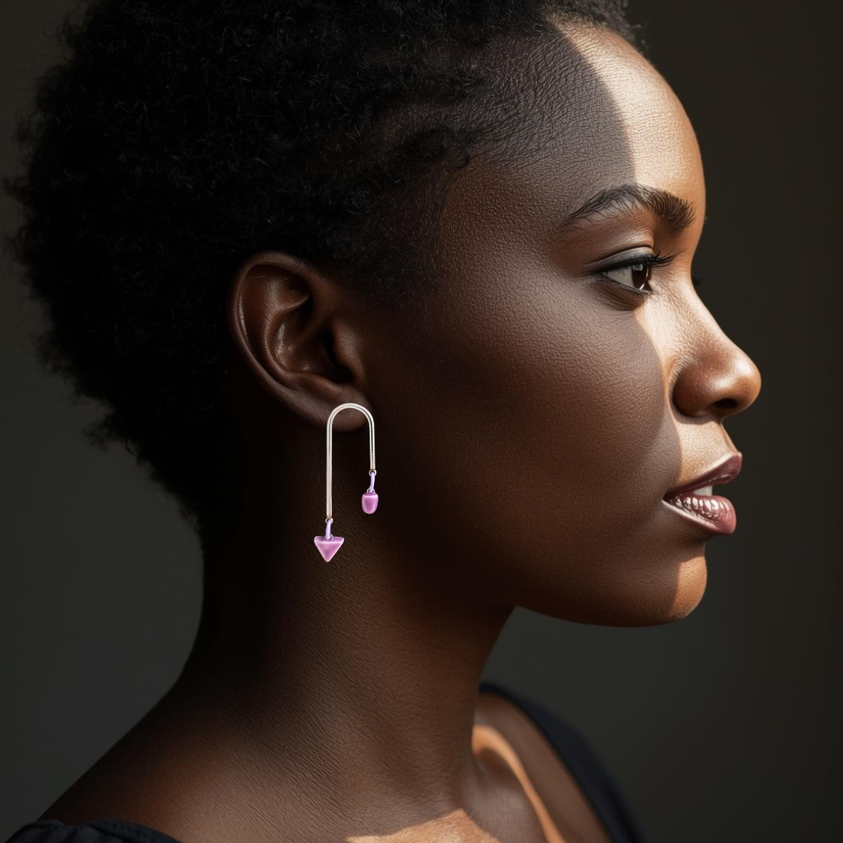 Profile of a woman wearing lillac geometric earrings against a dark background