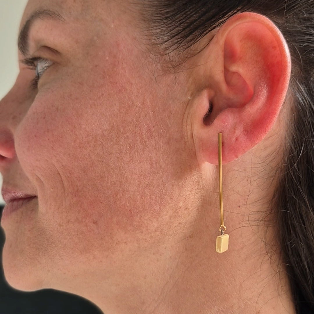 Close-up of a woman wearing gold earrings with a blurred background